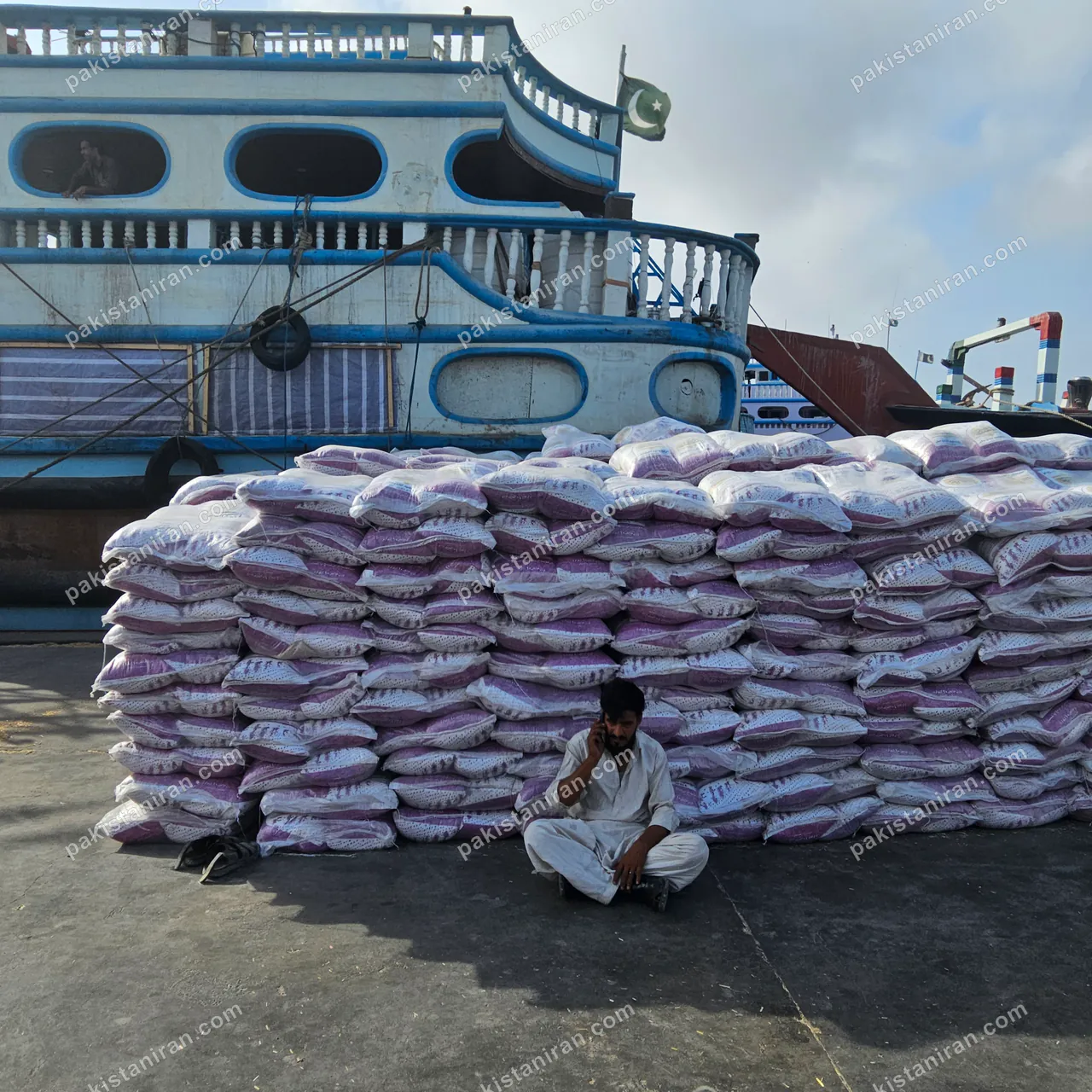 HAS Trading shipment: Rice stacked at the quay beside a moored launch, Pakistan flag flying